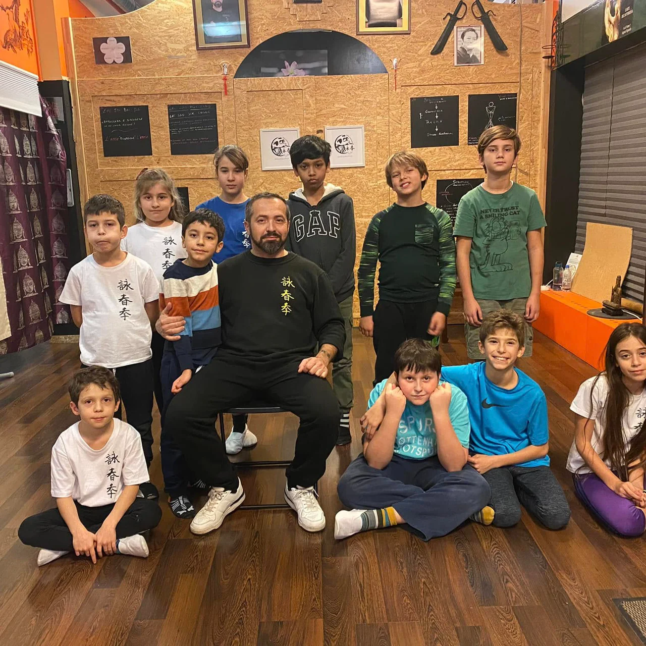 Bambini e ragazzi seduti attorno a Sifu Luca Bomba nella sala