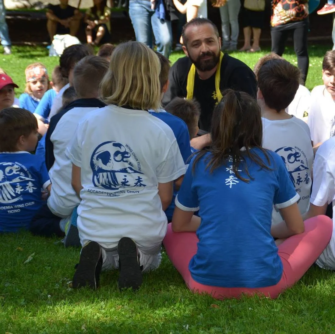 Sifu Luca Bomba con i bambini seduti sul prato, durante una lezione all'aperto